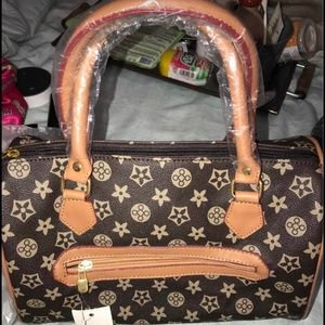 Woman’s brown zippered satchel with crossbody strap.